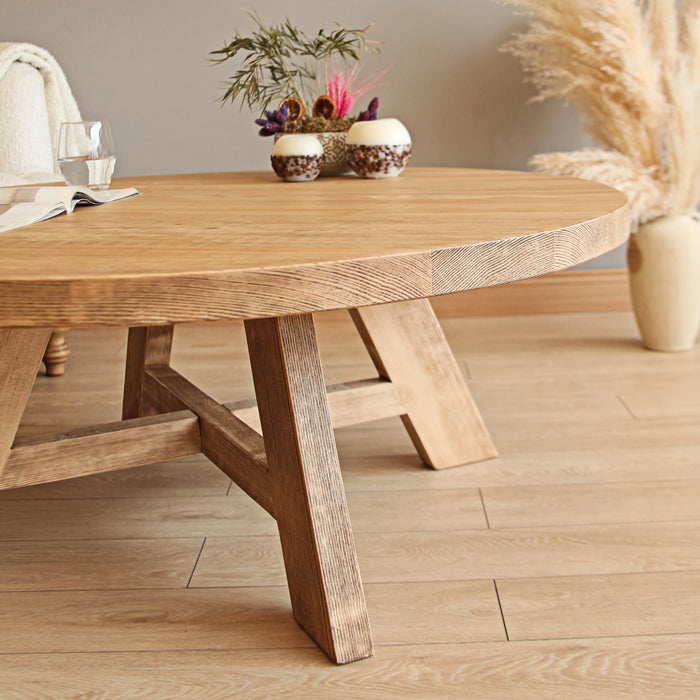 Close-up front view of the round coffee table, highlighting the leg details and the natural finish, showcasing the craftsmanship and design.