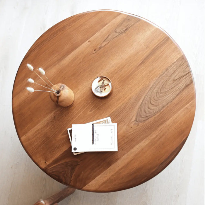 Top view of the Sidney Solid Wood Mid-Century Modern Round Coffee Table, highlighting the smooth walnut wood grain, rounded edges, and spacious tabletop, styled with decorative items for a modern touch.