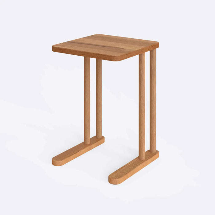 Side angle of the Solid Wood C Table next to a couch, highlighting its C-shaped structure that easily slides under furniture for convenience.
