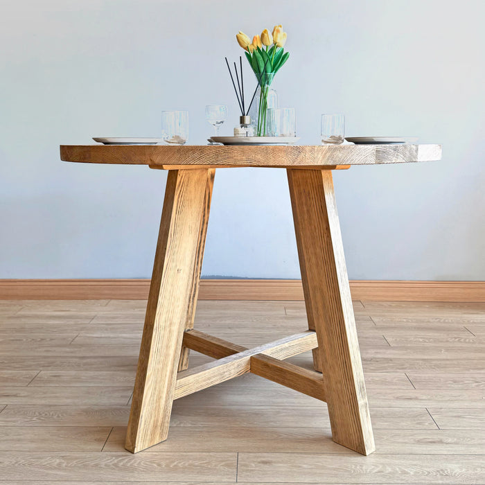 Wide shot of the Amber Round Farmhouse Dining Table with ambient lighting for an elegant look.