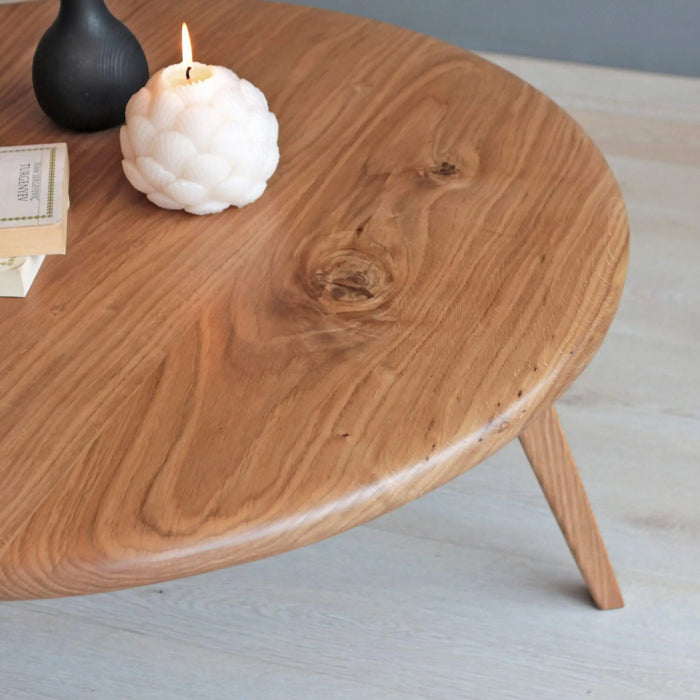 Crafted from high-quality solid oak, this Aura round coffee table offers timeless appeal with its smooth surface and mid-century modern style.