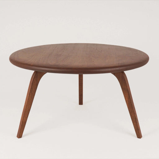 Front view of the round coffee table displaying its smooth tabletop and sturdy leg, set against a softly blurred background that complements the rustic aesthetic.