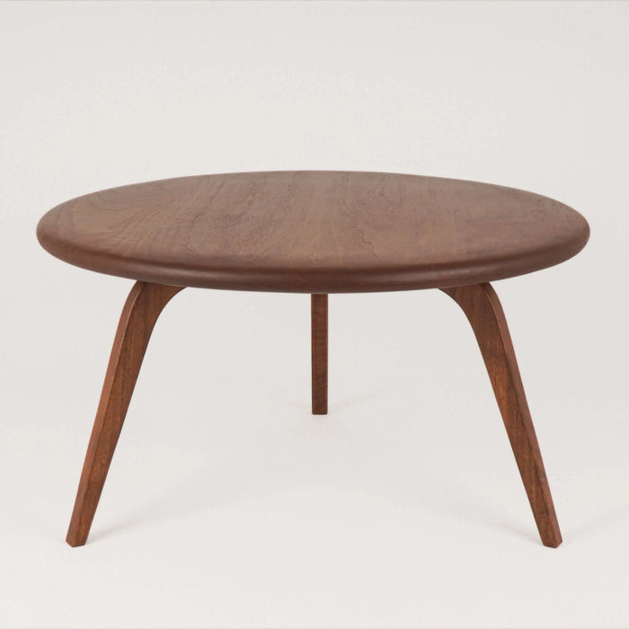 Front view of the round coffee table displaying its smooth tabletop and sturdy leg, set against a softly blurred background that complements the rustic aesthetic.