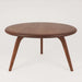 Front view of the round coffee table displaying its smooth tabletop and sturdy leg, set against a softly blurred background that complements the rustic aesthetic.