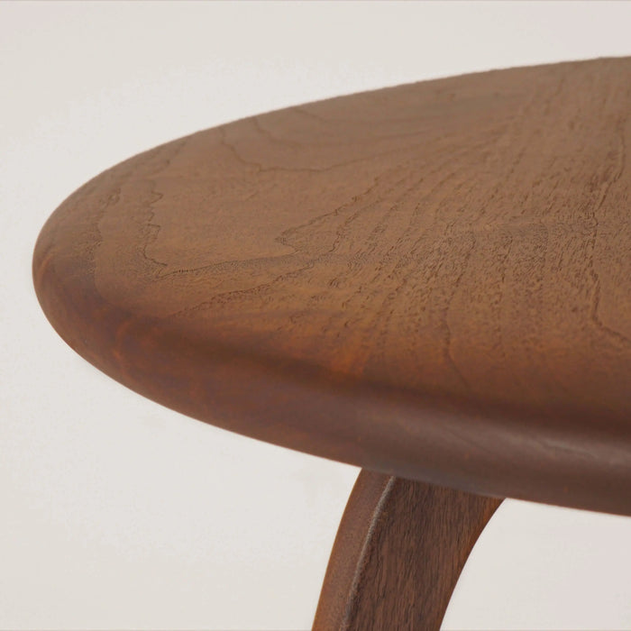 Close-up view of the tabletop from the front, showcasing the wood grains and rounded edge, highlighting the mid-century charm and natural beauty of the walnut wood.