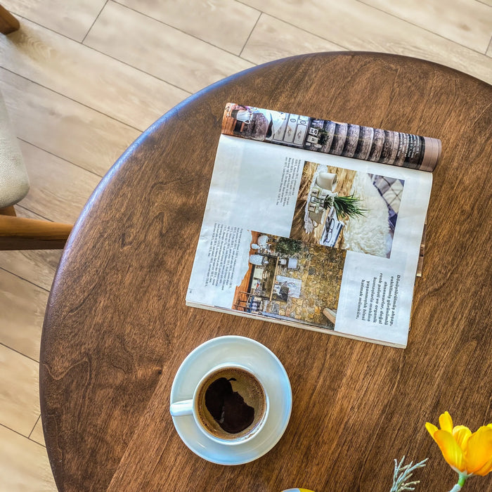 Top view of the round coffee table featuring decorative items on its surface, highlighting the rich wood grain and the stylish arrangement in a cozy setting.