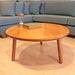 Round wood cocktail table featuring a smooth, minimalist design with tapered legs, perfect for small spaces.