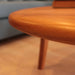 Side profile of the round wood cocktail table, featuring sturdy legs and a refined finish.