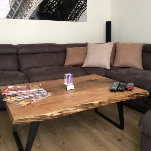 Denton Solid Walnut Wood Live Edge Coffee Table in front of a couch in a livingroom, with remote controllers on it