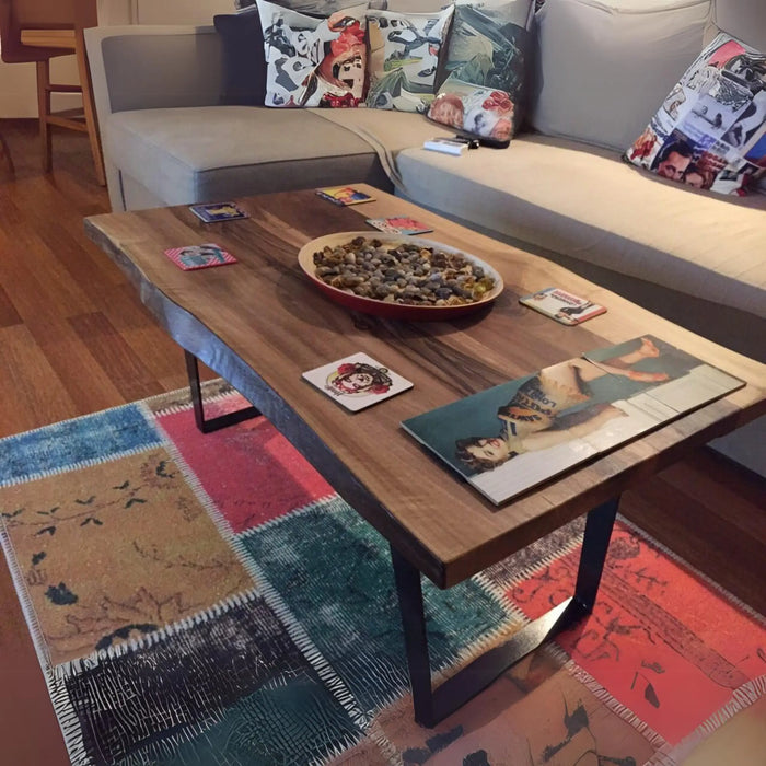 A diagonal view of the Denton Solid Walnut Wood Live Edge Coffee Table in a living room with accessories on it