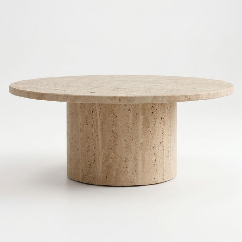 Eye-level studio shot of Dune Round Travertine Coffee Table showing natural porous stone texture and cylindrical pedestal base