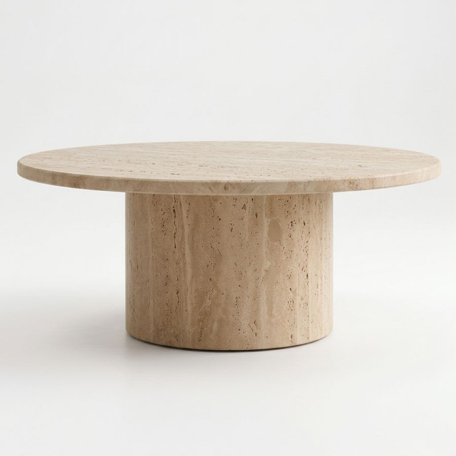 Eye-level studio shot of Dune Round Travertine Coffee Table showing natural porous stone texture and cylindrical pedestal base