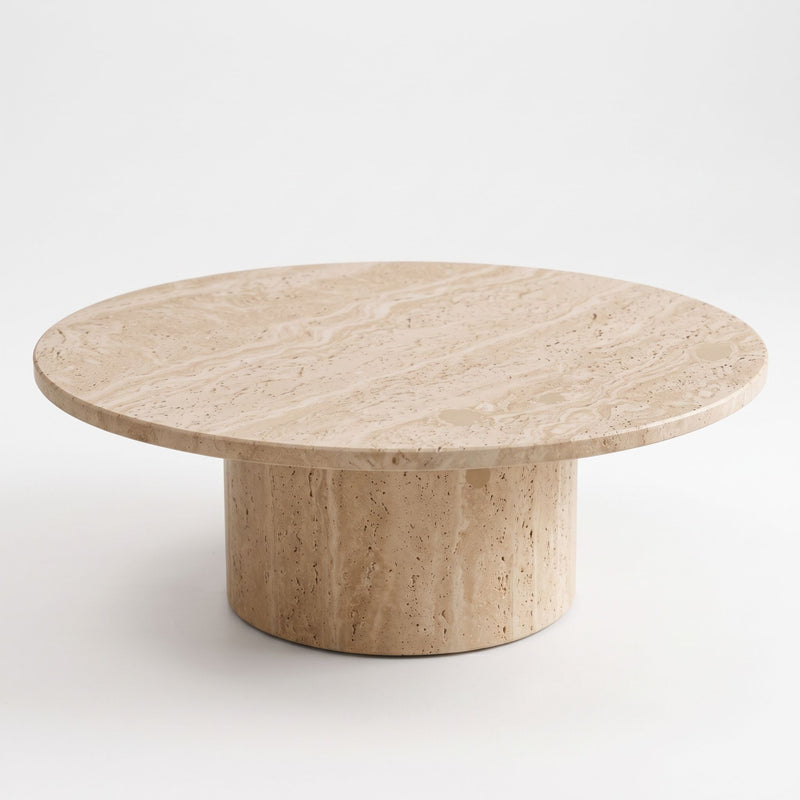 High three-quarter angle studio view of Dune Round Travertine Coffee Table displaying natural stone veining and cylindrical pedestal base