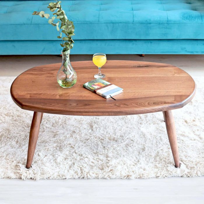 A front-facing shot of the oval coffee table, with the blue sofa and rug complementing the design