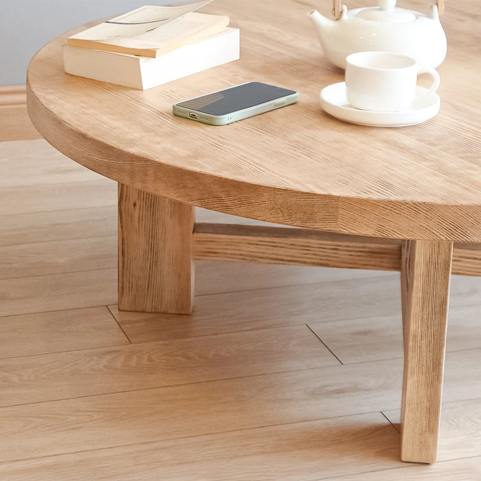 A side view of the Harlow round coffee table showcasing its solid construction and smooth wood surface.