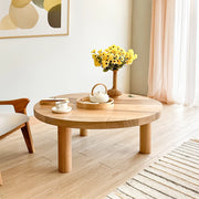 Minimalist light walnut round wood coffee table in a warm living room environment