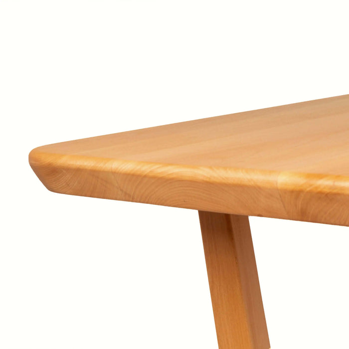 Angled perspective of the table in a bright, airy space, accentuating its warm, natural wood tone.