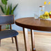 Side view of the Muse table in a well-lit dining space, emphasizing its mid-century charm and modern functionality.