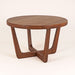 Solid wood round coffee table in walnut finish on a white background, showing mid-century design with smooth tabletop and iconic wooden legs.