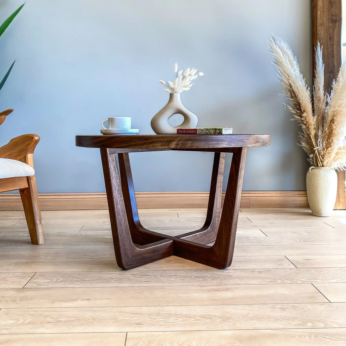 Front view of solid wood round coffee table in walnut, captured from a low angle to highlight sturdy mid-century legs and smooth tabletop.