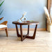 Diagonal low-angle view of a solid walnut wood round coffee table, highlighting sturdy wooden legs and smooth tabletop finish.
