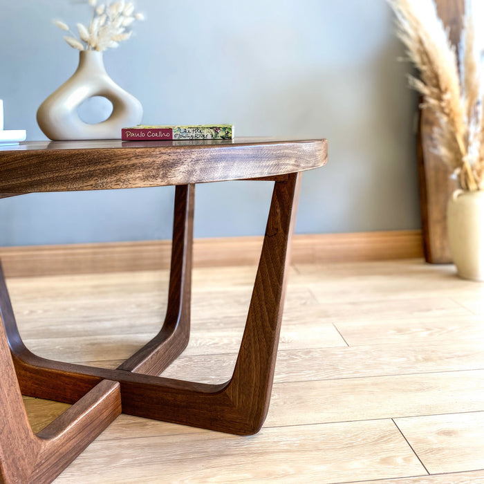Close-up view of the right side of a solid walnut wood round coffee table, highlighting the sturdy construction, leg design, and quality craftsmanship.