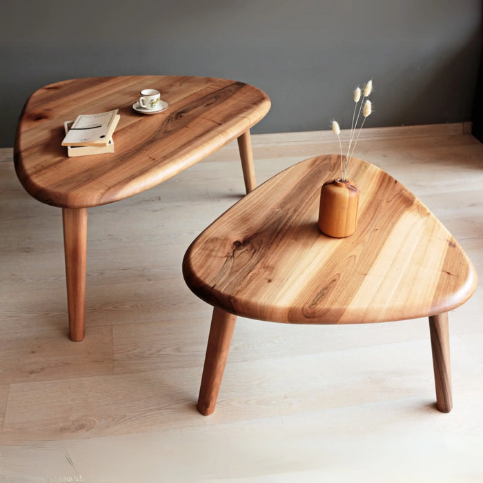 Two nested coffee tables separated, each with decor, shot from a slightly overhead angle against a plain wall background.