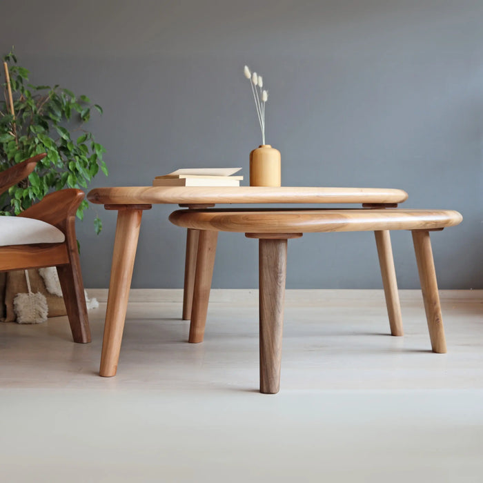 Front view of the walnut wood coffee table, with visible tapered legs, a blue couch, and parquet flooring in the background.