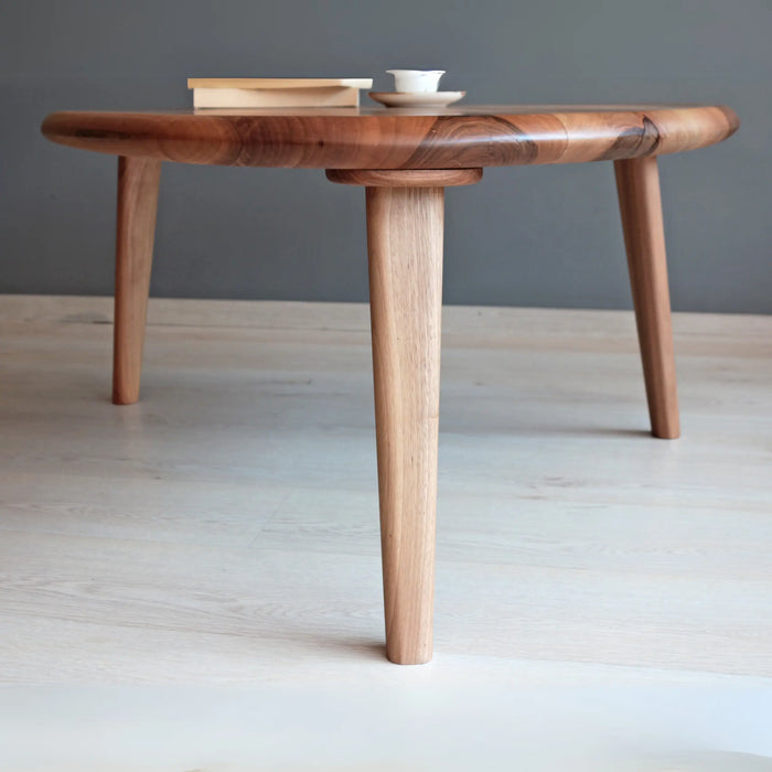 Close-up view of the coffee table’s leg and smooth walnut tabletop detail.