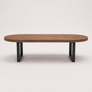 Oasis oval walnut coffee table with a medium brown wood grain top and a black metal frame base, shown against a plain light gray background.
