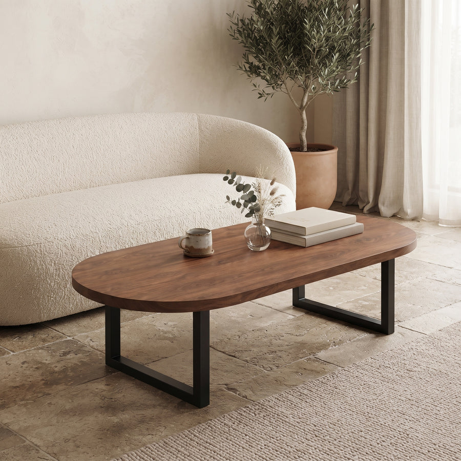 An oval wooden coffee table with a dark walnut finish and black metal legs