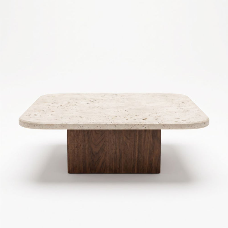 Eye-level straight-on studio shot of Pera Square Travertine Coffee Table featuring a rounded-corner beige stone top and solid walnut block base