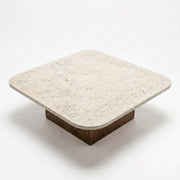 Detailed studio shot from high angle showing rounded-corner beige travertine stone top surface and solid walnut block base on Pera Square Coffee Table