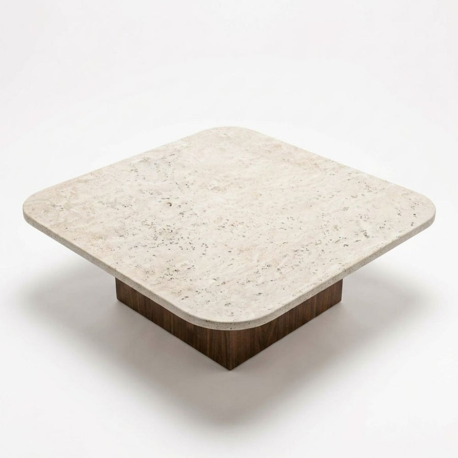 Detailed studio shot from high angle showing rounded-corner beige travertine stone top surface and solid walnut block base on Pera Square Coffee Table