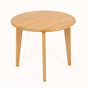 Petra Round Wood Dining Room Table Solid Oak Wood with a light oak finish, featuring a smooth circular top and three tapered legs, shown on a plain white background.
