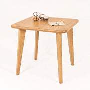 Petra Square Wood Dining Table Solid Oak Wood with rounded corners and tapered legs, styled with small decorative bowls and a notebook on a clean white background.