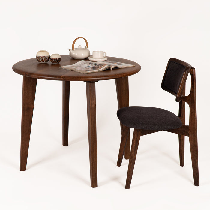 The Petra round wood dining room table in a showroom setting, styled to emphasize its mid-century aesthetic.