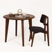 The Petra round wood dining room table in a showroom setting, styled to emphasize its mid-century aesthetic.