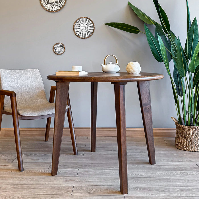 Side view of the round wood dining room table, highlighting the tapered mid-century modern legs