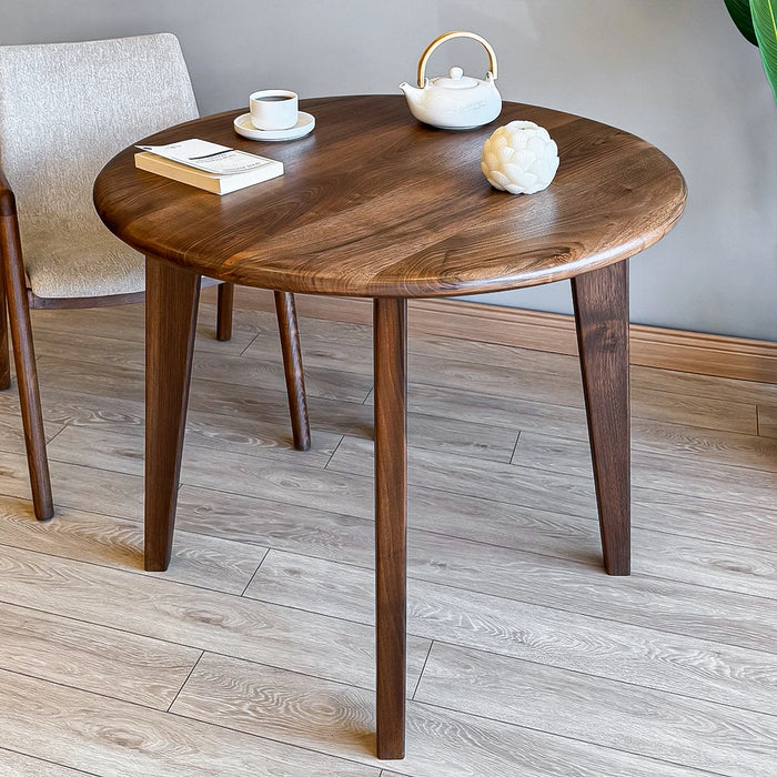 A dining room setting featuring the round wood table, styled with chairs and decor for a minimalist look