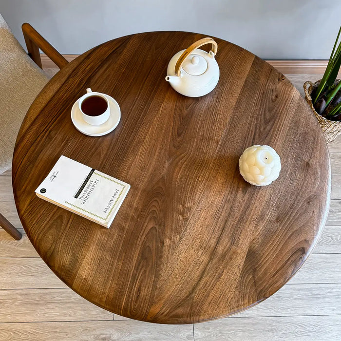 The round wood dining table styled with tableware, offering an elegant dining setup.