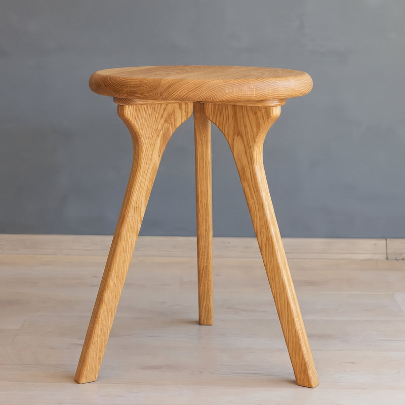 Sidney Round Side Table Solid Oak Wood with a round seat and three splayed legs, shown against a neutral gray wall and light wood floor.