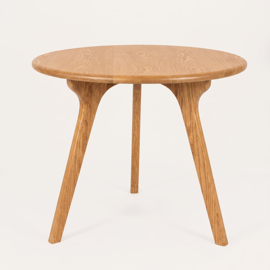 Sidney Circular Dining Table Solid Oak Wood – Mid-Century Modern Design with a natural oak finish, featuring a smooth circular tabletop and three tapered splayed legs, shown against a plain off-white background.