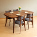Side angle of a solid hardwood dining table showcasing smooth edges and tapered legs.