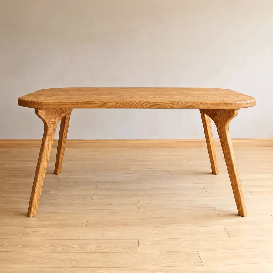 Sidney Rectangle Dining Table Solid Oak Wood – Mid-Century Modern Design with a thick rounded rectangular top and four tapered legs, shown on a light wood floor against a neutral beige wall.