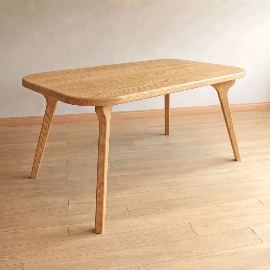 Sidney Rectangle Dining Table Solid Oak Wood – Mid-Century Modern Design with rounded rectangular legs and tapered splayed legs, shown in a minimalist room with light wood flooring and a neutral wall.