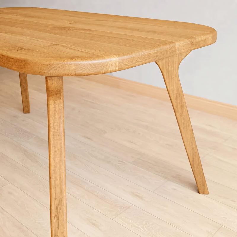 A close-up of Sidney Rectangle Dining Table Solid Oak Wood – Mid-Century Modern Design showing the tabletop and one leg, set on a light wood plank floor against a neutral light gray wall.
