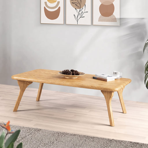 Sidney Rectangular Coffee Table Solid Oak Wood – Mid-Century Modern Designwith angled legs, styled in a minimalist living room setting with a bowl of pinecones and a stack of books on top.