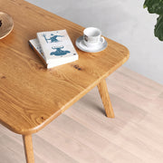 Sidney Rectangular Coffee Table Solid Oak Wood – Mid-Century Modern Design with rounded corners and tapered legs, styled with a book and a white teacup on a saucer in a bright room with light wood flooring.