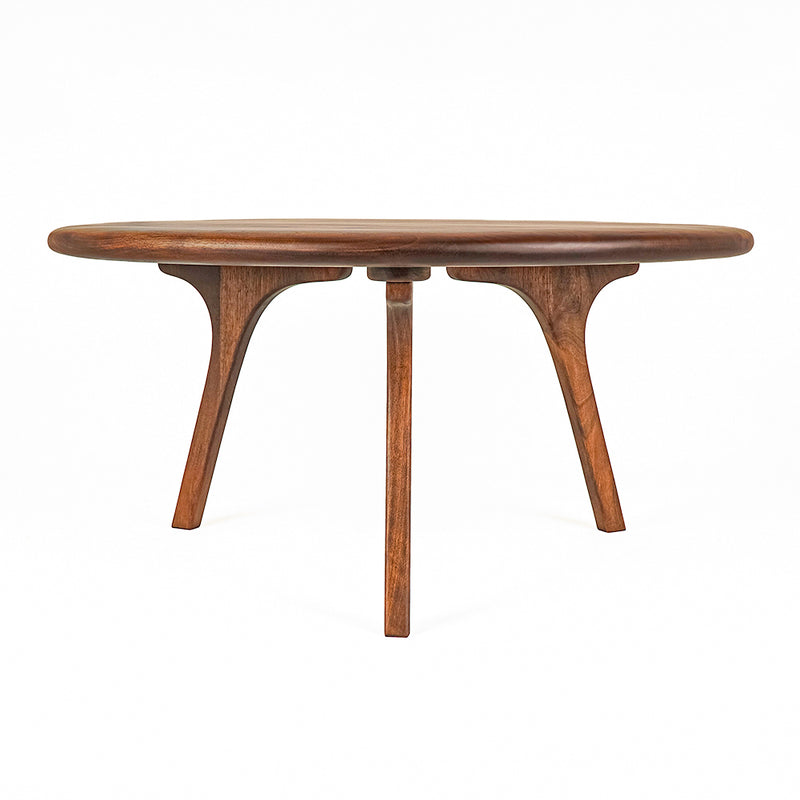 Sidney Round Coffee Table - Solid Walnut Wood - Mid Century Modern Designwith a rounded oval top and three sculptural curved legs, shown on a solid white background.